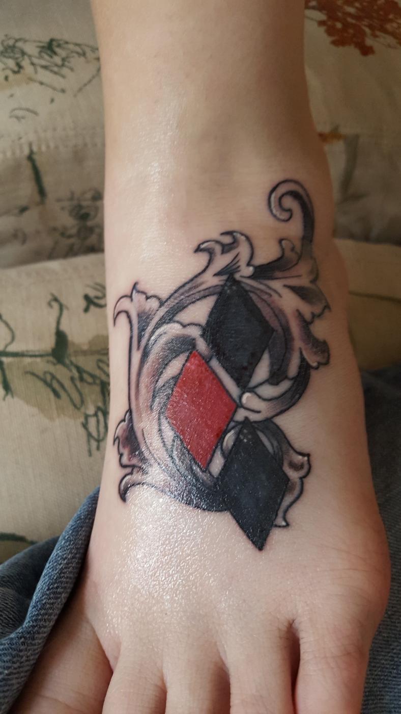 A red and black diamond tattoo on the top of a foot