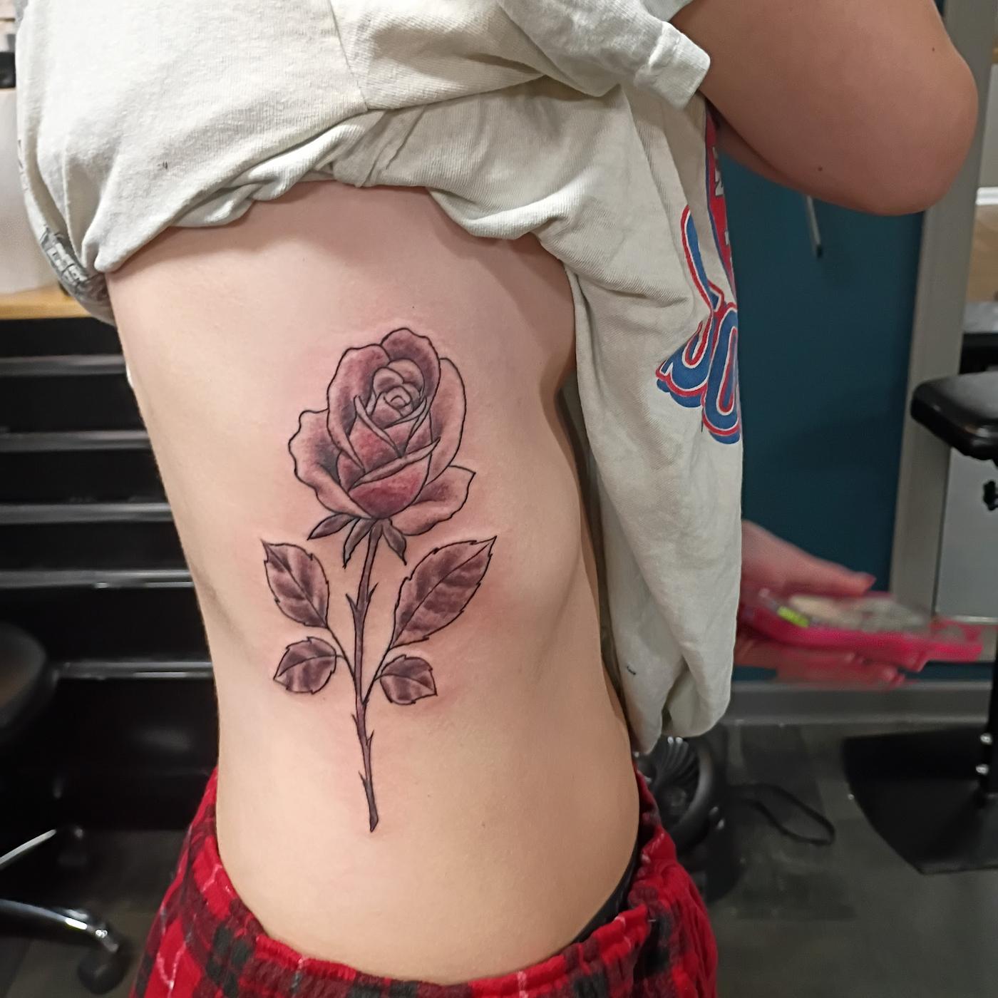 A fine line rose tattooed on the ribs